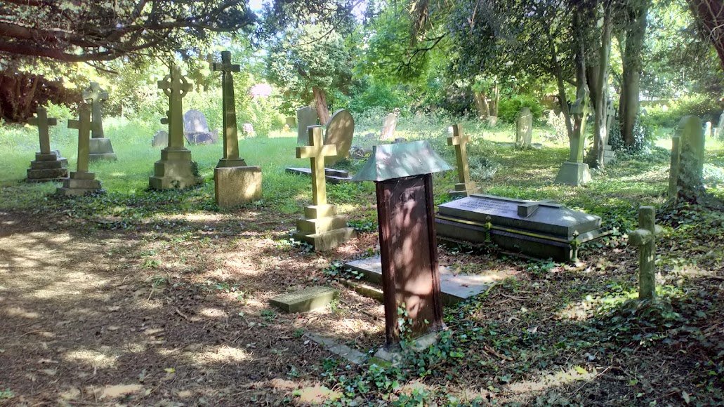 The peaceful churchyard at St Nicholas, with weathered crosses among the trees