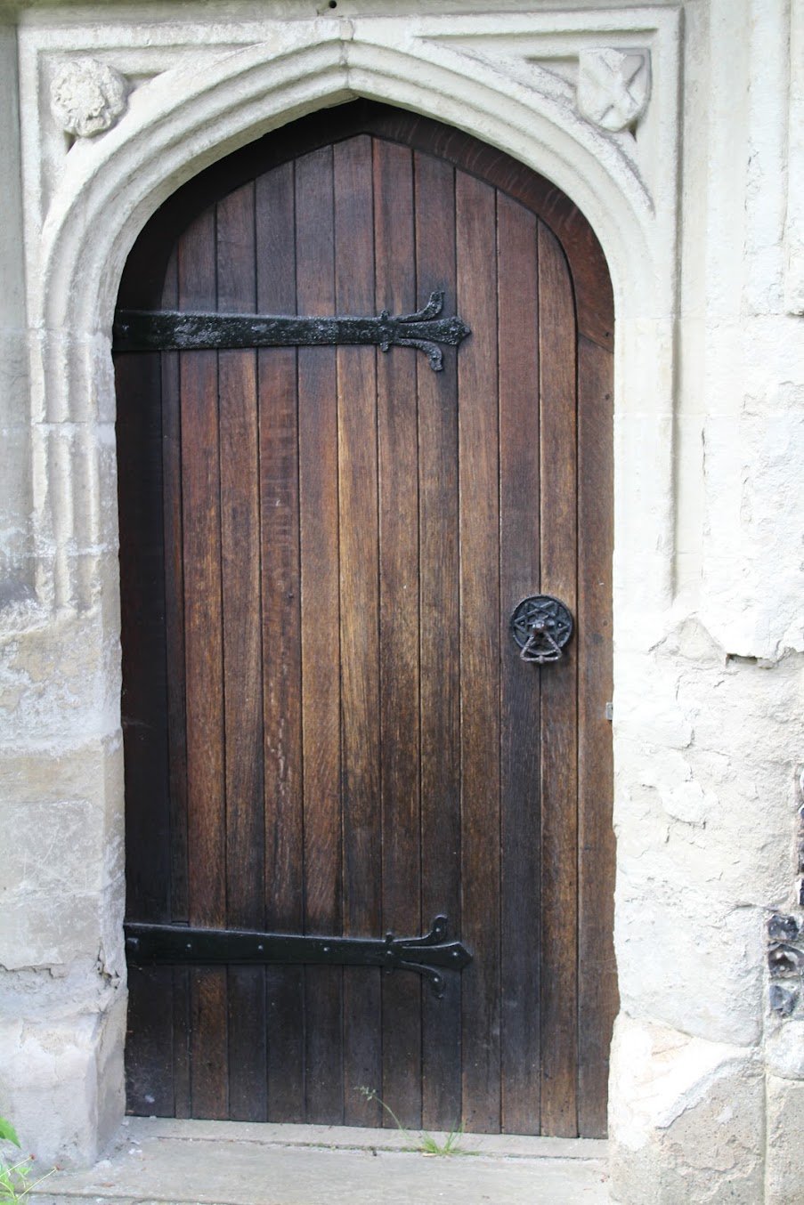 A Gothic arched oak door with wrought-iron hinges