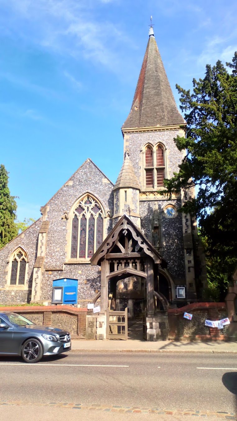 The flint tower and broach spire of St Nicholas Church rising against a clear blue sky