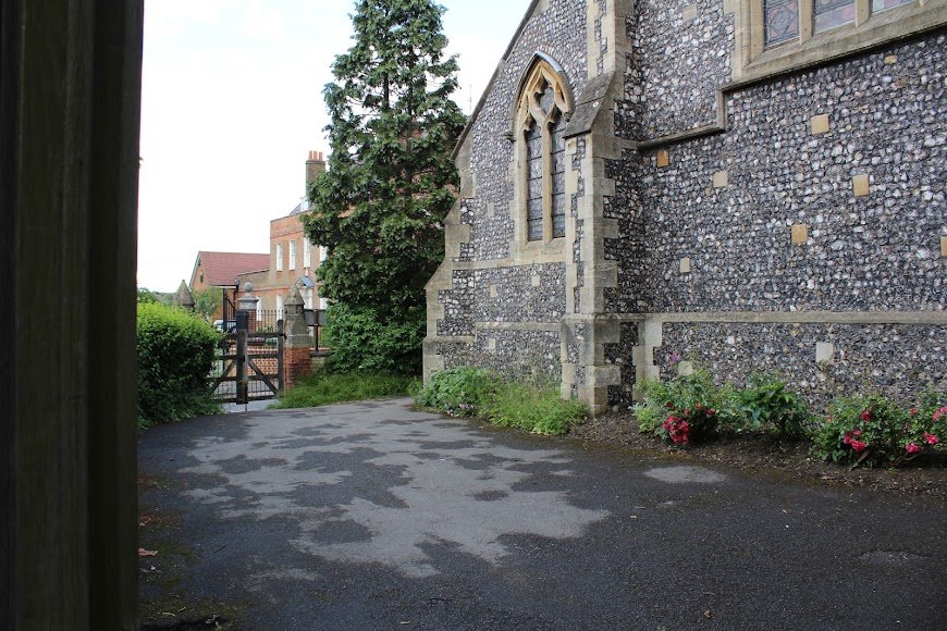 A flower-lined path beside the flint wall of St Nicholas Church