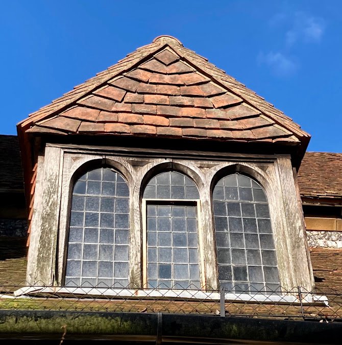 A dormer of triple lancet windows against a blue sky